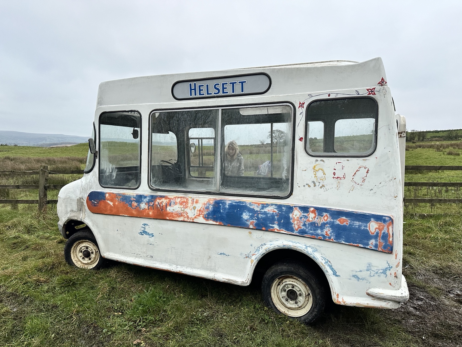A weathered Helsett ice cream van in a field before restoration